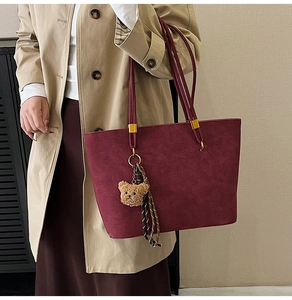 Vue détaillée du sac cabas bordeaux mat avec breloque ours et accessoire foulard