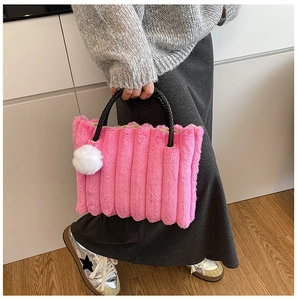 Detail of bright pink faux fur tote bag featuring pleated texture and black woven handle