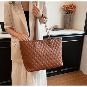 Close-up of caramel brown quilted tote bag showing fine leather texture and large capacity