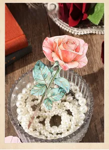 Close-up of gold-rimmed rose bookmark placed in a pearl bowl with vintage backdrop