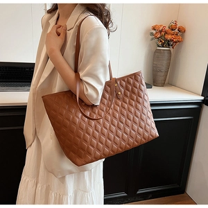 Brown quilted tote bag with shoulder straps worn by model in an office setting