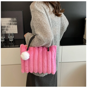 Detail of pink plush tote bag with vertical stripes and black woven handle on a model