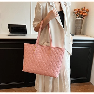 Detailed view of a pink quilted tote bag featuring golden studs and a spacious design