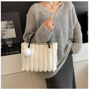 Detail of white plush tote bag featuring vertical quilting and black woven handle