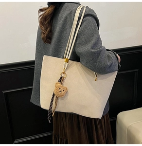 Détail d'un sac cabas blanc crème avec texture en daim et pendentif en forme d'ours