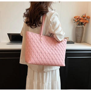 Pink quilted tote bag with golden metal buckle detail shown in an office setting