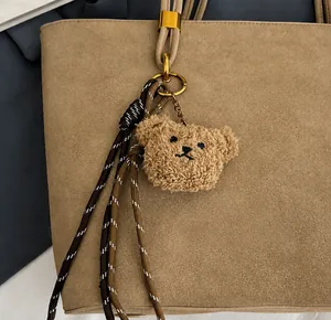 Détail du bijou de sac ours en peluche avec corde tressée et crochet sur sac kaki
