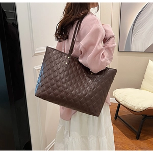 Detailed view of dark brown quilted tote bag in soft leather with gold stud accents