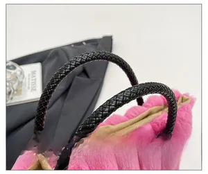 Detail of pink plush tote bag with striped texture and black braided leather handles