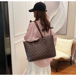 Detail shot of a dark brown quilted tote bag on a model in a minimalist indoor setting