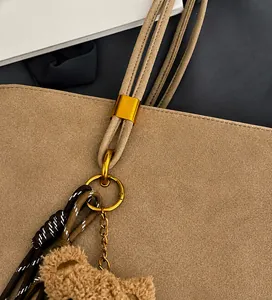 Détail du sac bandoulière en daim kaki avec ferrures dorées et breloque ours