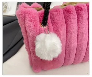 Detail of rose red plush tote bag with striped texture and soft white pom-pom charm