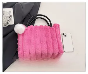 Detail of rose pink plush tote bag featuring black woven handles and soft pompom charm