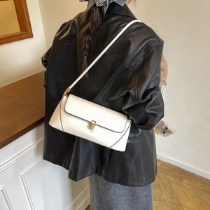 Sac baguette blanc minimaliste avec fermoir doré porté sur un mannequin en veste de cuir noir