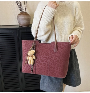 Detail of burgundy leopard print tote bag with soft texture and plush bear charm