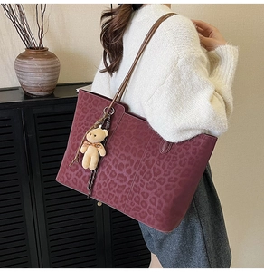 Detail view of burgundy tote bag with leopard print and cute teddy bear charm