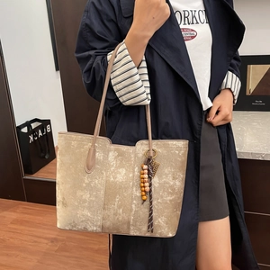 Premium champagne gold tote bag with textured metallic finish and tassel charm accessory