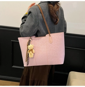 Detail of pink leopard embossed tote bag with teddy bear charm and striped ribbon