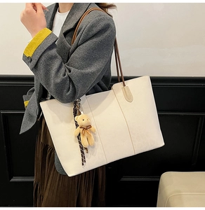 Close-up of white oversized tote bag featuring a cute bear charm and striped ribbon detail