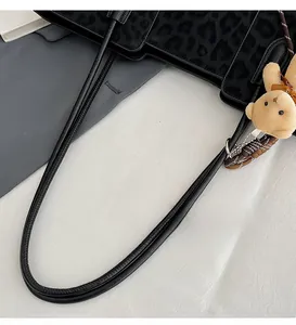 Detail of black leopard print suede tote bag with leather trim and bear plush charm