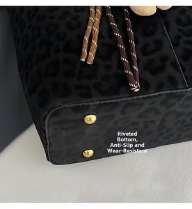 Detail view of leopard print tote bag base with protective golden metal rivets and texture