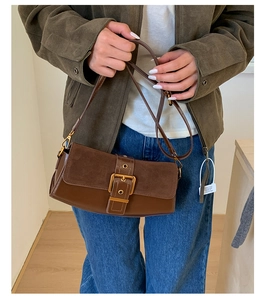 Detail of dark brown vintage baguette bag featuring mixed textures and bronze buckle