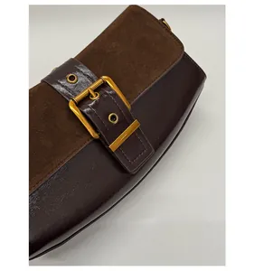 Close-up of brown suede and smooth leather stitching with gold buckle on underarm bag