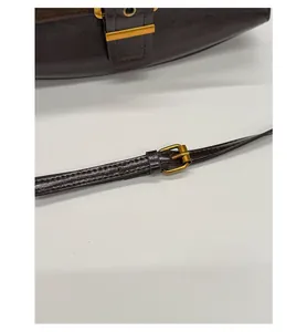 Close-up of the adjustable brown leather shoulder strap with a vintage gold metal buckle