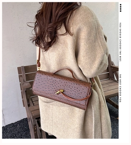 Brown ostrich texture handbag with gold twist lock shown in a stylish outdoor setting