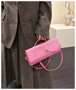 Detail of rose pink ostrich texture handbag with golden twist lock and long shoulder strap