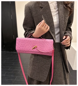 Pink ostrich pattern baguette bag with gold clasp shown on a grey tweed suit model