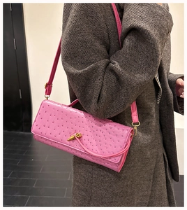 Detail of pink ostrich texture shoulder bag with gold twist lock on grey tweed jacket