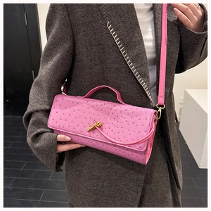 Close-up of pink ostrich texture handbag with a decorative gold knot twist lock detail