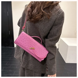 Macro detail of ostrich textured bright pink bag with elegant gold metal twist lock