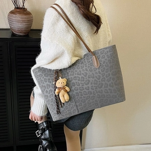 Large leopard print tote bag with brown handles and cute plush bear charm on shoulder