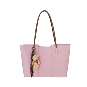 Pink leopard print tote bag with brown straps and plush bear charm on white background