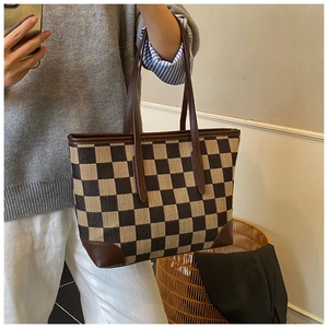 Detailopname van een grote geruite shopper van canvas met bruine lederen handvaten