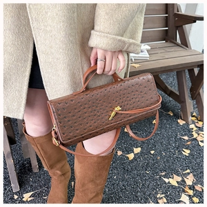 Close-up of brown ostrich texture leather bag with elegant gold metal twist lock