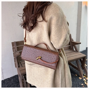 Macro view of brown ostrich texture handbag with golden twist lock and leather strap