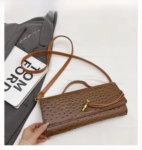 Detail of brown ostrich pattern leather bag with a vintage gold metal flip-lock closure