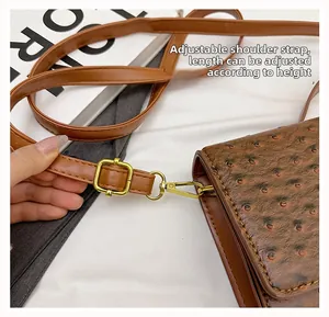 Detail of adjustable shoulder strap with gold metal buckle on brown ostrich pattern bag