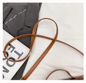Close-up of the brown leather shoulder strap with golden metal buckle on a baguette bag