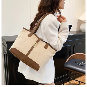 Détail d'un grand sac cabas en toile avec cuir marron contrasté et fermoir doré