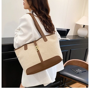 Close-up of contrast stitching on canvas tote bag with brown leather and gold lock