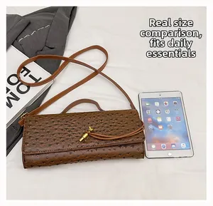 Brown ostrich texture handbag with golden twist lock shown next to a tablet for scale