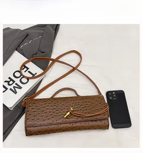 Macro view of brown ostrich texture handbag with gold twist lock on white background