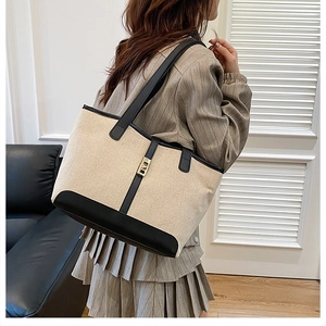 Detail of color-block tote bag with beige canvas, black leather straps and gold metal buckle