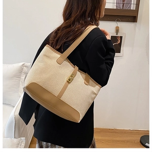 Detailed view of the canvas tote bag with brown leather trim and golden square buckle