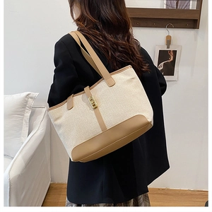 Close-up of contrast large tote bag with beige canvas, brown leather and gold buckle