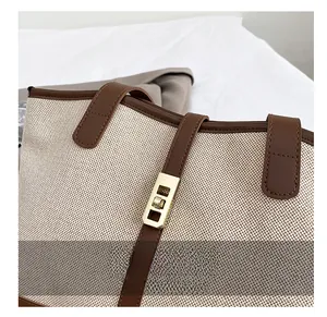Detailed macro view of the gold rectangular twist lock on a canvas and leather tote bag